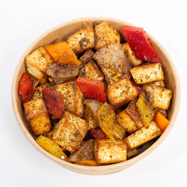 Close-up of paneer tikka with red and yellow bell peppers in a bowl.