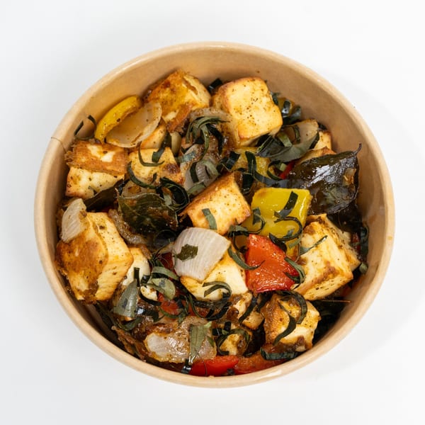 Indian paneer dish with bell peppers, onions, and herbs in a brown bowl.