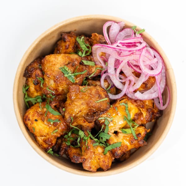 H1B's Chicken 65, a spicy fried chicken dish, garnished with red onions and cilantro.