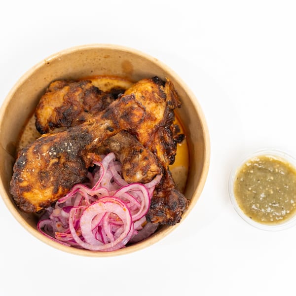 H1B's chicken drumsticks with red onion slices and a side of green chutney.
