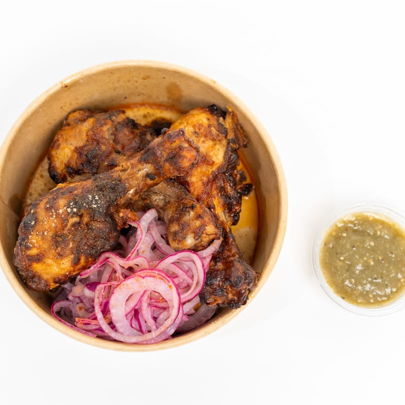 H1B's chicken drumsticks with red onion slices and a side of green chutney.